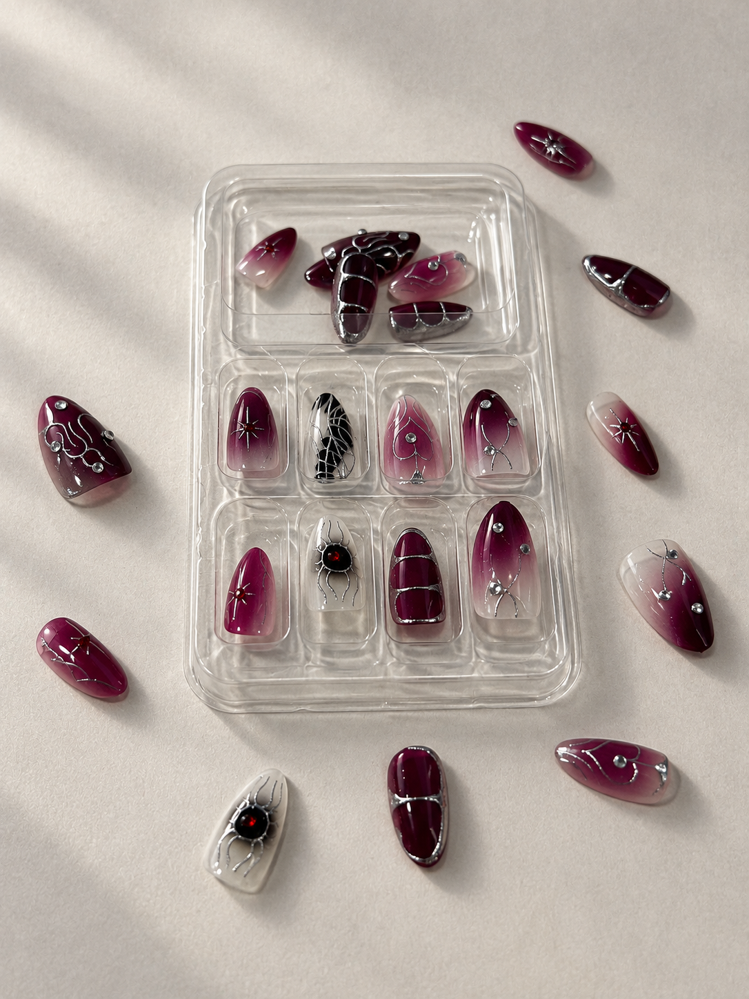 Dark plum Halloween press on nails in tray with loose nails around
