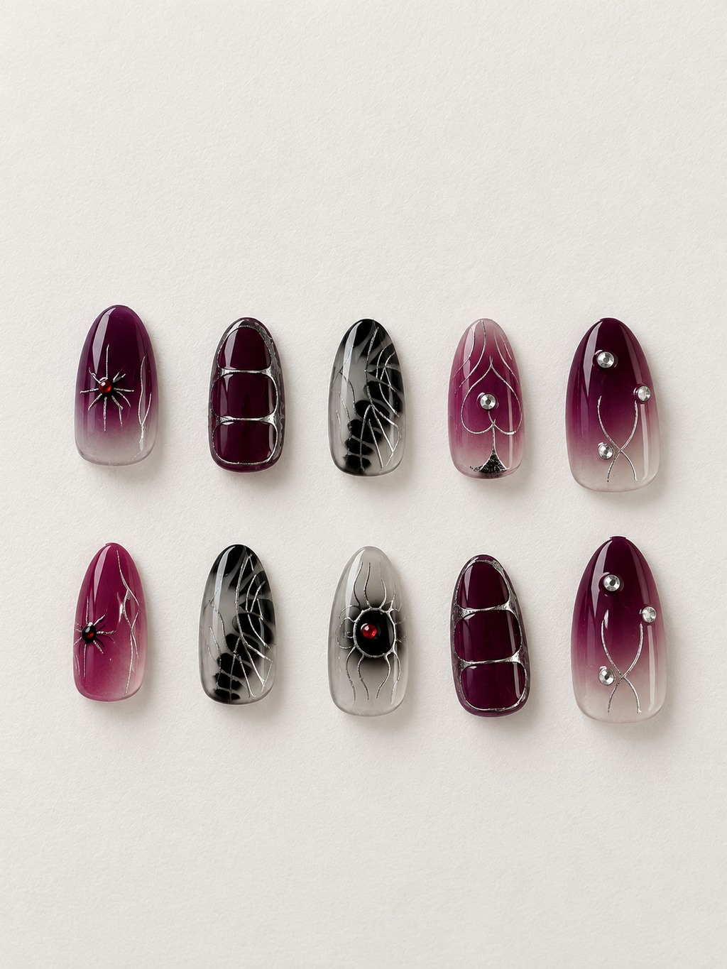 10 dark plum and smoky black press on nails flat lay with silver spider details