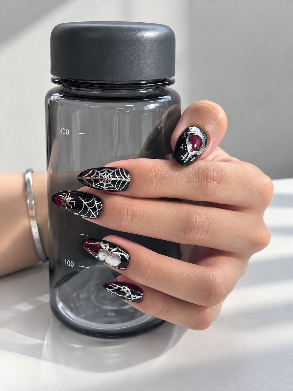 Dark Halloween press on nails worn holding a bottle